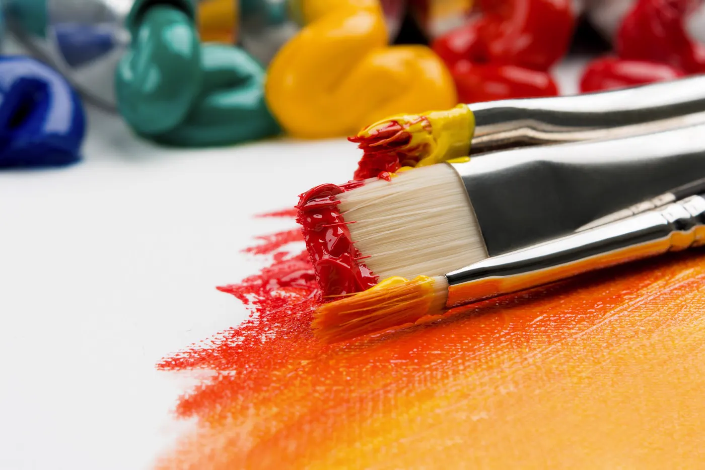 Pinceaux et peinture rouge orangée sur toile