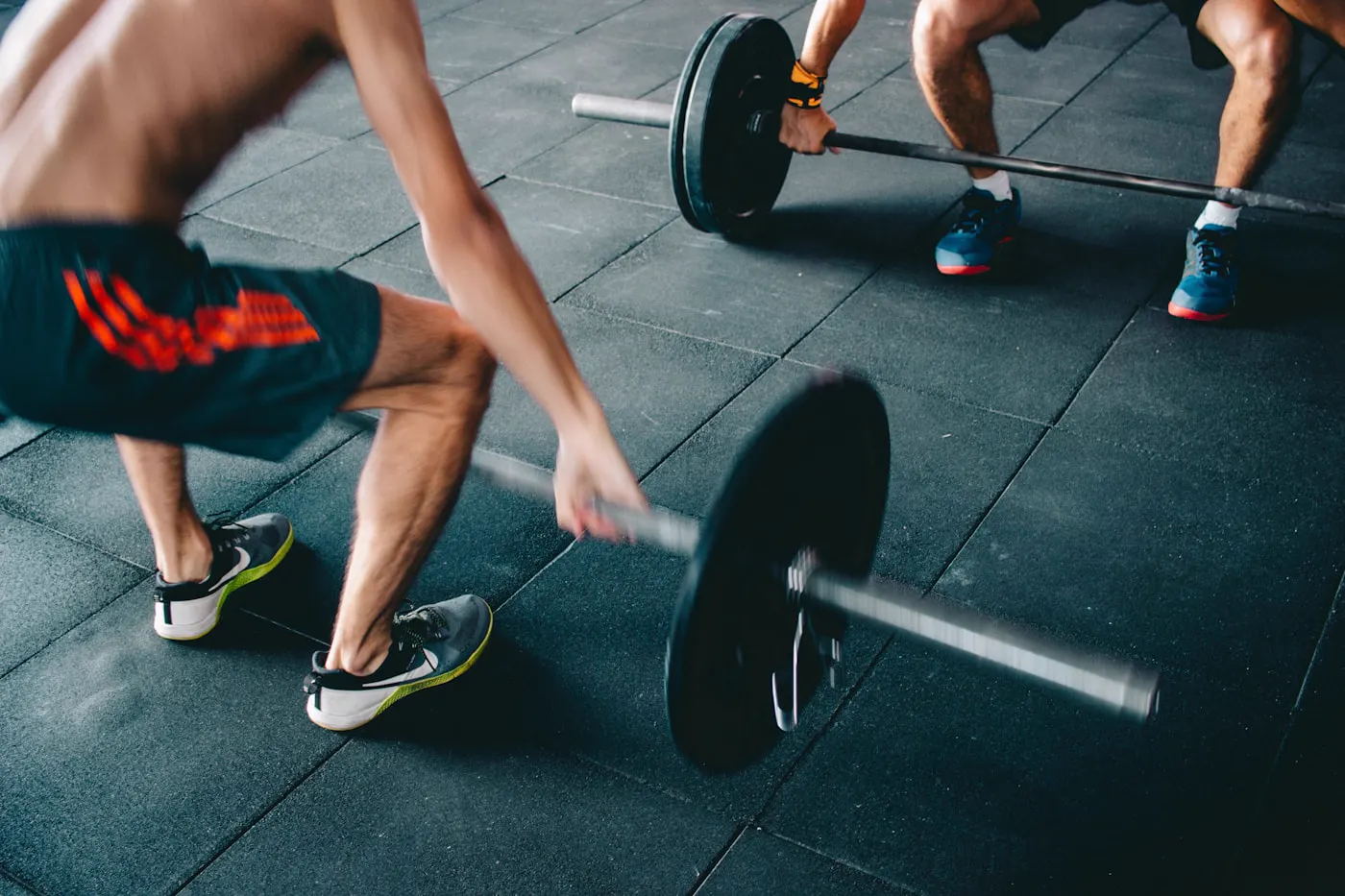 Athlètes travaillant la force avec une barre en salle de sport